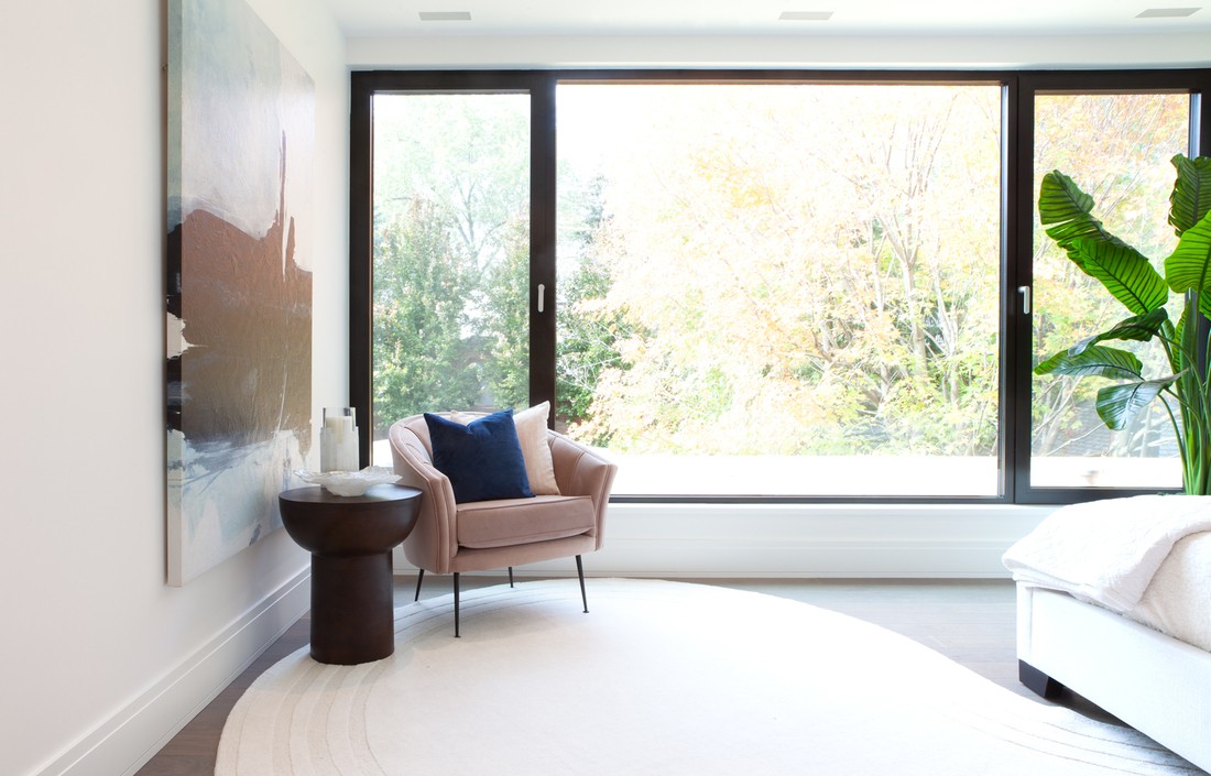 Expansive window behind chair and side table in bedroom in Toronto custom home