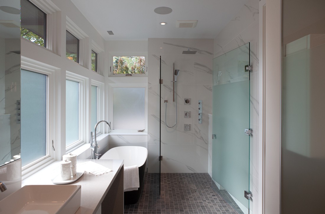 Primary bathroom with marble tiling, film windows, and curbless shower & tub combo