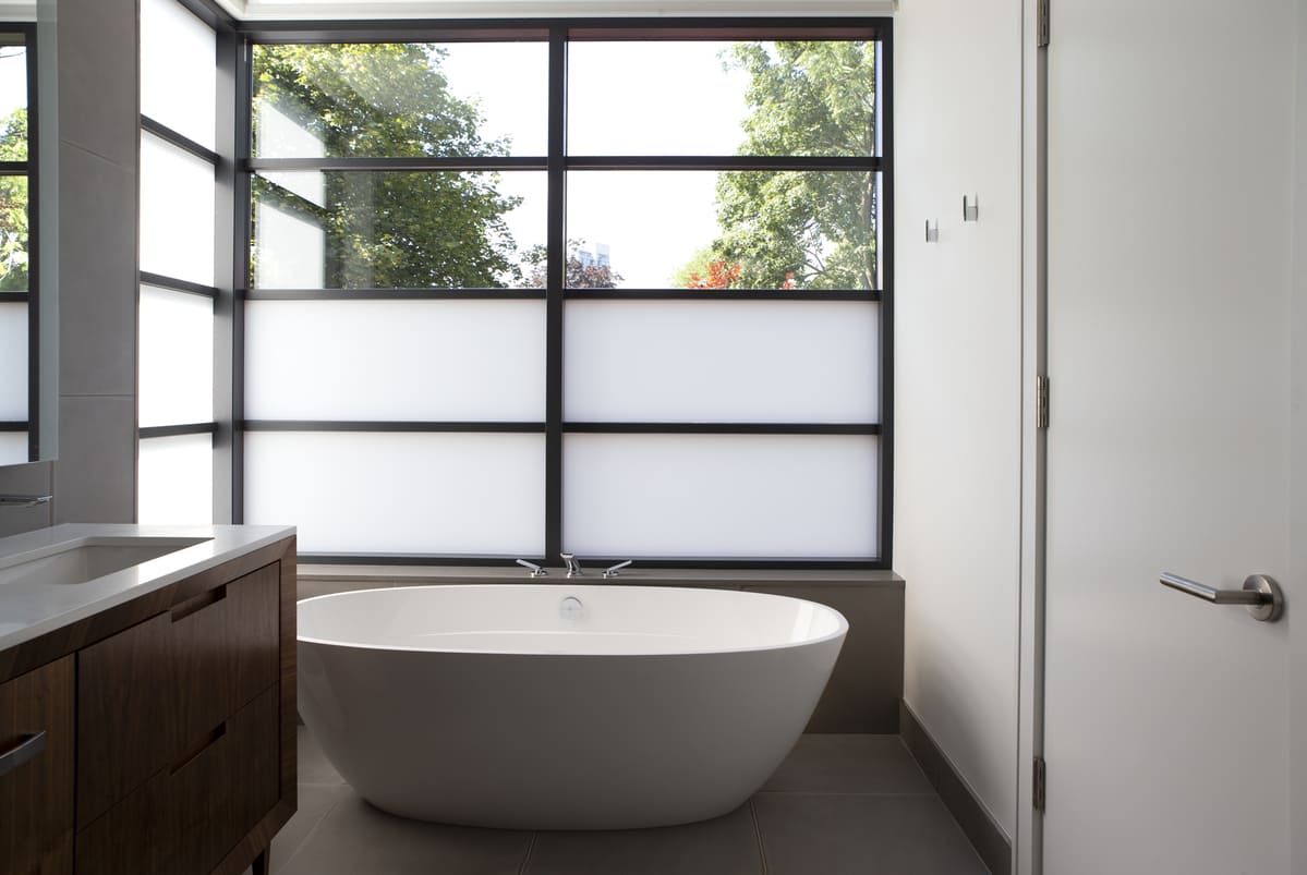 Bathroom with window film in front of freestanding tub in Toronto by SevernWoods