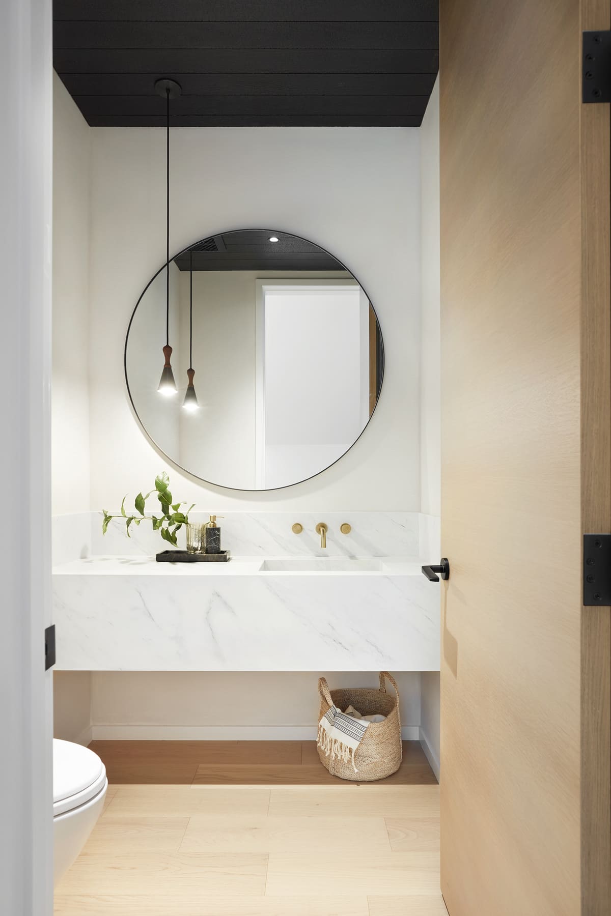 Door opening to floating bathroom vanity in minimalist style custom home by SevernWoods