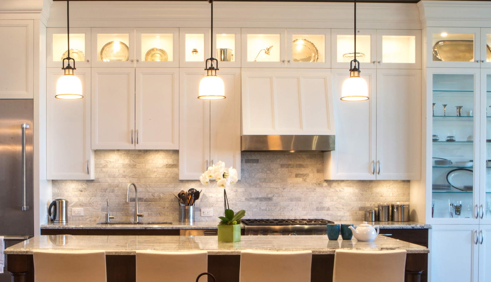 Glass panel ceiling cabinets in Leaside, Toronto custom home with three pendant lights above island