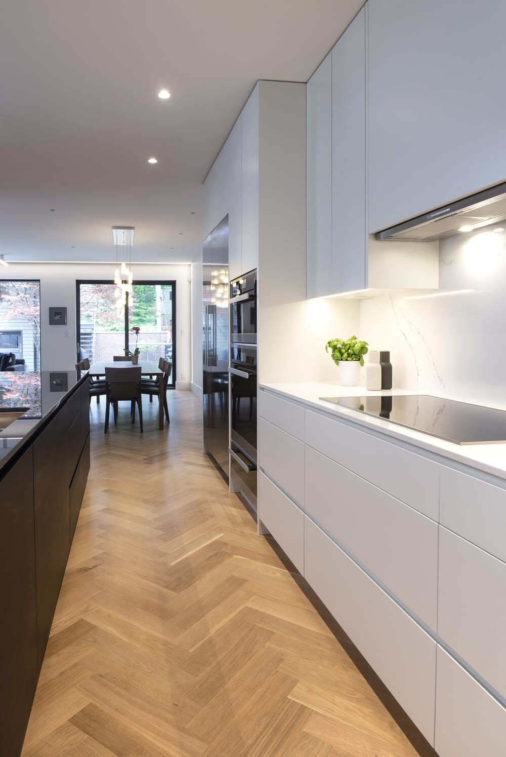 Minimalist style kitchen with white flat panel cabinets and herringbone flooring in Toronto by SevernWoods