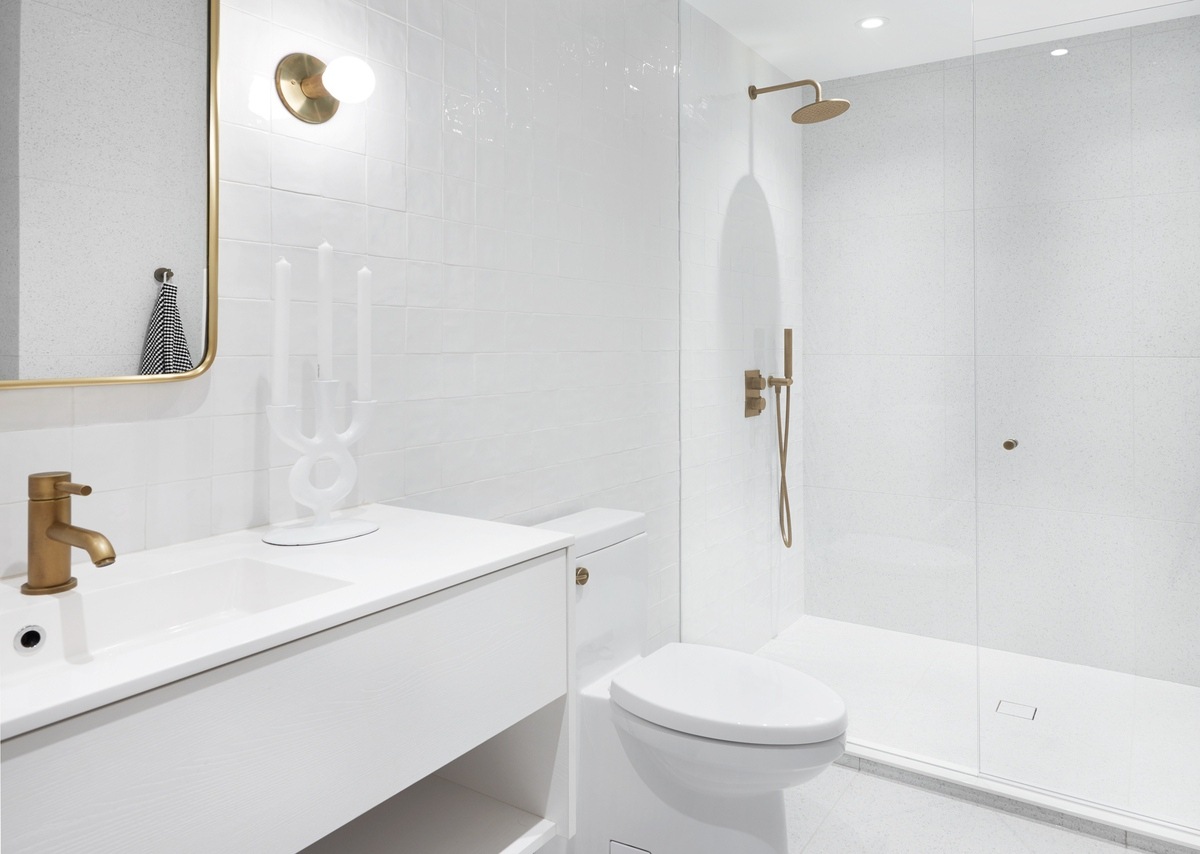 Minimalist style luxury white bathroom with gold fixtures in Toronto by SevernWoods