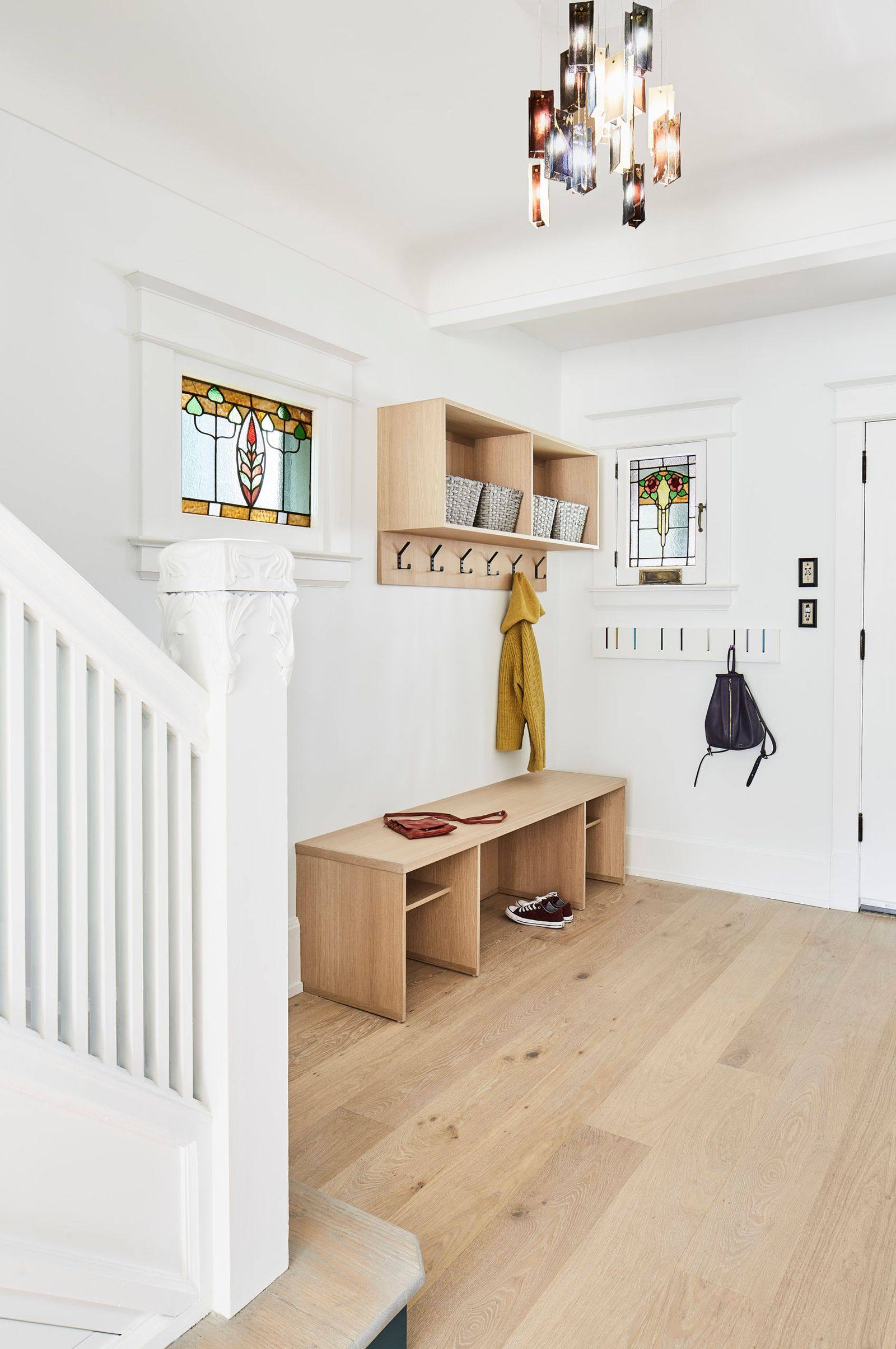 Entryway of Toronto home with traditioinal stained glass window slot and custom shelving and hooks